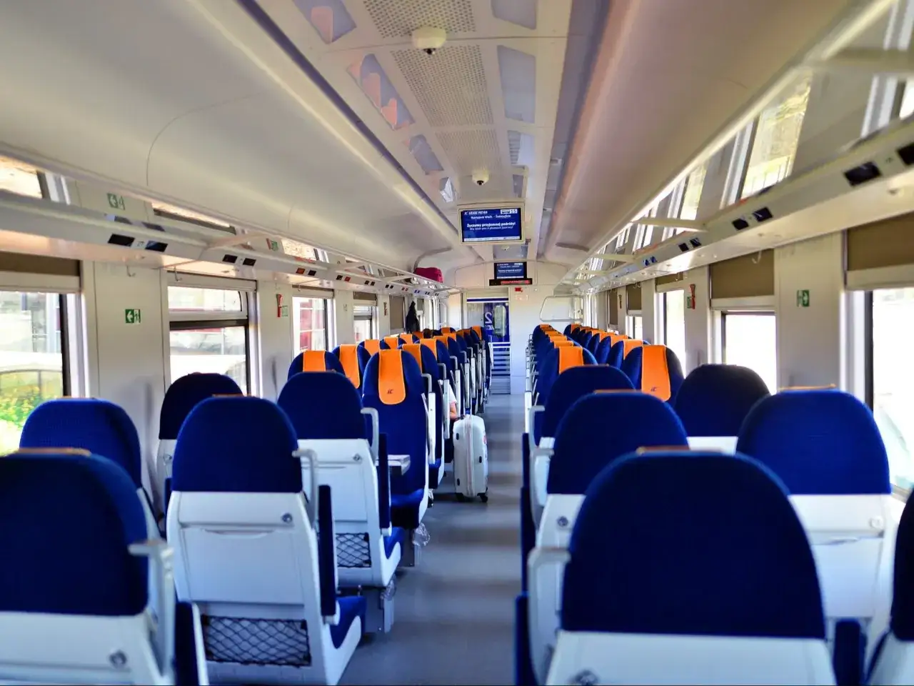 Wnętrze nowoczesnego pociągu z wygodnymi siedzeniami i dostępem do intercity wifi.