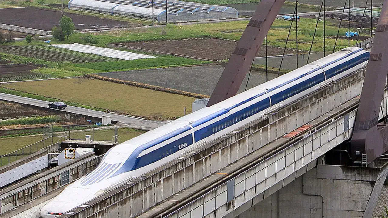 Szybki pociąg maglev sunie po estakadzie nad polami.