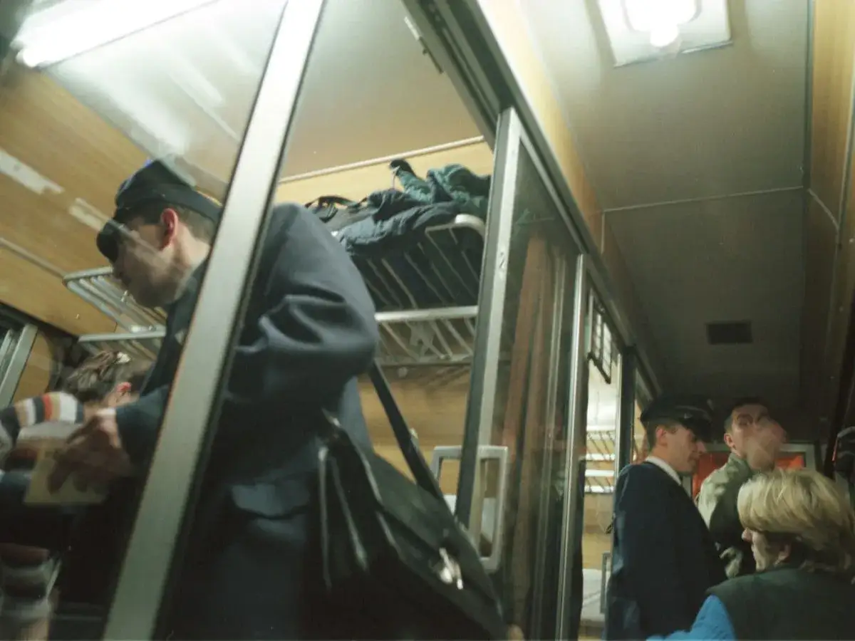 Konduktor sprawdza bilety w wagonie PKP. Może to być kontrola dopłaty do biletu ulgowego.