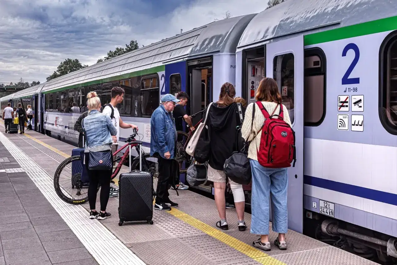 Ludzie z bagażami i rowerem czekają na pociąg PKP. Okazja na zniżkę 78 % pkp!