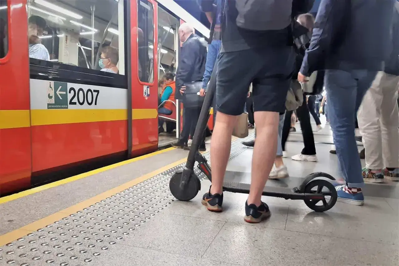 Osoba z hulajnogą elektryczną czeka na pociąg.