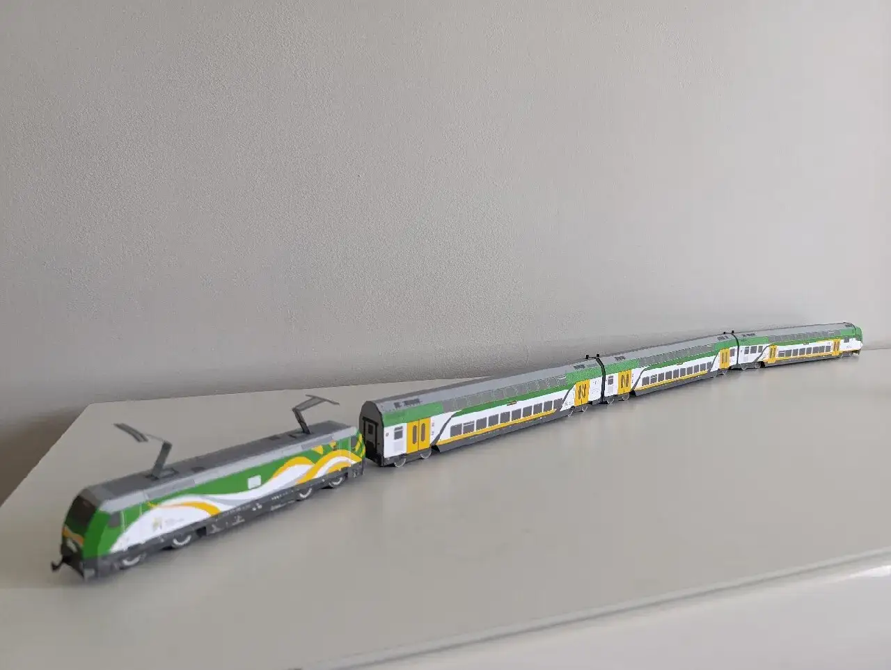 Model pociągu PKP Intercity z lokomotywą przypominającą bombardiera, w zielono-biało-żółtych barwach, gotowy do podróży.