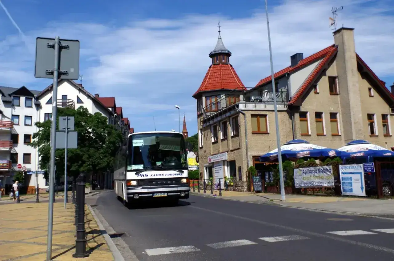 Autobus PKS Kamień Pomorski jedzie ulicą. W tle kamienice i wieżyczka, jakby z Lublina do Białej Podlaskiej.