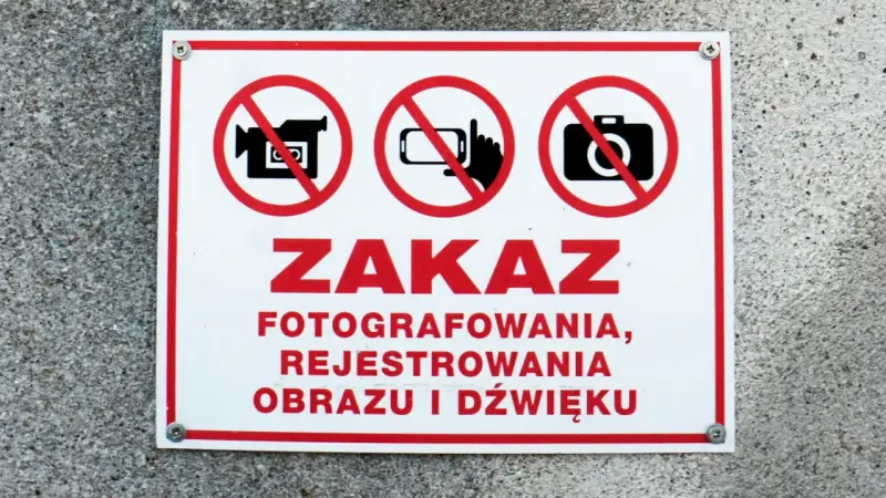 Tabliczka z czerwonym obramowaniem informuje o zakazie fotografowania, rejestrowania obrazu i dźwięku.