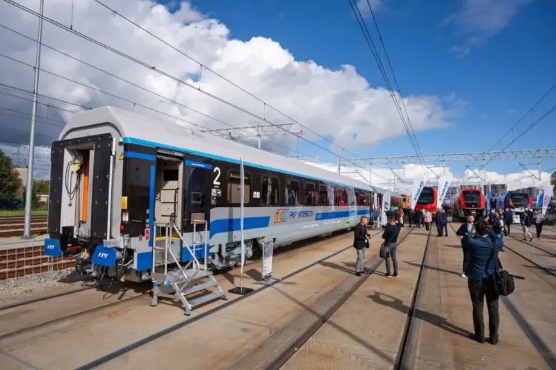 Nowy wagon PKP Intercity z niebieskim pasem, gotowy na podróż. W tle inne nowoczesne składy ec.